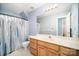 A well-lit bathroom features a white countertop, wooden cabinets, and a shower with patterned curtain at 10230 Blackstock Rd, Huntersville, NC 28078
