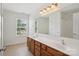 Bright bathroom features a double sink vanity, large mirror, and natural light from the window at 10303 Dominion Village Dr, Charlotte, NC 28269