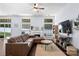 Spacious living room featuring hardwood floors, a sectional sofa, a modern ceiling fan, and a white mantel fireplace at 13517 Silver King Ct, Huntersville, NC 28078