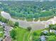 Panoramic aerial shot showcasing homes along a river's bend, complemented by lush lawns and tree cover at 5015 Foxbriar Trl, Charlotte, NC 28269