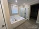 This bathroom features tile floors, a soaking tub with tile surround, and a glass enclosed shower at 707 Marion Dr, Matthews, NC 28105