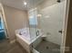 A bathroom showcasing tile floors, a glass enclosed shower, and a soaking tub with tile surround at 707 Marion Dr, Matthews, NC 28105