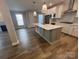 Open kitchen features white cabinets, stainless steel appliances, a large island with a sink, and hardwood floors at 707 Marion Dr, Matthews, NC 28105