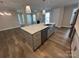 Open kitchen features a large island with sink, stainless appliances, hardwood floors, and connects to living area at 707 Marion Dr, Matthews, NC 28105