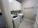 A well-lit laundry room features a washer, dryer, cabinets, tile floor, and hanging rack at 707 Marion Dr, Matthews, NC 28105