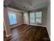 A living room has hardwood floors, crown molding, neutral colored walls, and three windows for natural light at 707 Marion Dr, Matthews, NC 28105
