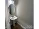 This powder room includes a pedestal sink, a round mirror, and updated lighting at 707 Marion Dr, Matthews, NC 28105