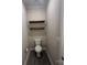 A cozy powder room with dark wood floating shelves, a toilet, and dark tile floor at 707 Marion Dr, Matthews, NC 28105
