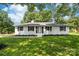 Charming single story home with a well manicured lawn, black shutters, and mature trees overhead at 104 Spargo St, Gastonia, NC 28056