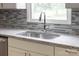 Close-up of a stainless steel sink with granite countertops and a gray tile backsplash at 104 Spargo St, Gastonia, NC 28056