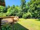 A large backyard featuring green grass, a deck, and large trees at 125 Circle Dr, Mount Holly, NC 28120