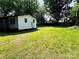 A green lawn with trees and an outbuilding with white siding and dark trim at 20016 Walter Henderson Rd, Cornelius, NC 28031