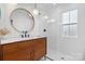 Stylish bathroom features a wood vanity, round mirror, and modern glass enclosed shower at 2704 Kool Park Ne Rd, Hickory, NC 28601