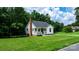 A charming cottage-style home with a brick chimney surrounded by a green lawn and lush trees at 2704 Kool Park Ne Rd, Hickory, NC 28601