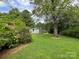 Lush backyard with mature trees framing the view of a cinderblock building and adjacent red brick house at 506 Hearne Farm Rd, Mount Gilead, NC 27306