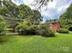 Lush green backyard featuring a well-maintained lawn and mature landscaping around a brick home at 506 Hearne Farm Rd, Mount Gilead, NC 27306
