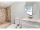 Bright bathroom with a tiled shower and white vanity under a round mirror at 6930 Culloden More Ct, Charlotte, NC 28217