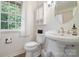 Cozy bathroom with a pedestal sink, toilet, and window providing natural light at 12101 Ranburne Rd, Mint Hill, NC 28227