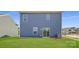 Exterior view of home with blue siding and sliding glass door leading to the well-maintained backyard lawn at 143 Astor St, Troutman, NC 28166