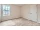 Neutral bedroom with a window for natural light and carpet flooring with an adjacent door for closet space at 143 Astor St, Troutman, NC 28166