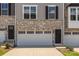 Close-up exterior of townhome featuring stone accents, dark door, and white garage door at 2040 Dornoch Rd, Tega Cay, SC 29708