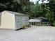 Backyard features large sheds and a house nestled in a lush, green environment with lots of surrounding trees at 257 Rolling View Dr, New London, NC 28127