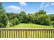 Expansive backyard with lush greenery and mature trees, seen from a wooden deck railing at 8106 Strawberry Point Dr, Charlotte, NC 28215