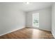 Simple bedroom with hardwood floors, a ceiling light, and a bright window offering outside views at 8106 Strawberry Point Dr, Charlotte, NC 28215
