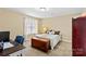 Comfortable bedroom featuring a large window, a desk, a classic-style bed and neutral wall color at 105 Whimbrel Ln, Mooresville, NC 28117