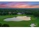 Stunning sunset aerial view of golf course with a large pond and luxury home in the background at 300 Eagle Bend Dr, Waxhaw, NC 28173