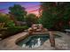 Backyard pool with rock waterfall feature, surrounded by lush greenery and stone paving at 300 Eagle Bend Dr, Waxhaw, NC 28173
