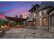 A stunning outdoor entertainment area featuring a stone patio, fireplace, and outdoor kitchen at twilight at 300 Eagle Bend Dr, Waxhaw, NC 28173