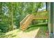 The wooden back deck with stairs overlooks the lush green lawn and wooded landscape at 7 S Coulter Ave, Newton, NC 28658