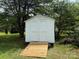 View of the white backyard shed with light brown ramp leading to the double doors at 3320 Hunting Wood Ct, Gastonia, NC 28052