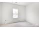 A bright, minimalist bedroom featuring clean white walls, a single window, and unfinished flooring at 4615 Yellow Poplar Ln, Concord, NC 28025