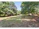 Wide shot of the backyard featuring mature trees and a picnic table at 2508 Wood Star Ct, Matthews, NC 28105