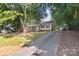 View of the home with an extra long driveway and mature trees at 2508 Wood Star Ct, Matthews, NC 28105