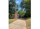 A long driveway leads to a blue-sided home with brick chimney, shaded by mature trees against a blue sky at 1320 Kings Cir, Shelby, NC 28150