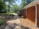 Exterior view of home's side yard featuring mature trees, and a stone walkway along a classic brick home at 1320 Kings Cir, Shelby, NC 28150