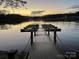 Wooden dock with boat slips leading out to a serene waterfront view at sunset at 4552 Sawgrass Ct, Denver, NC 28037
