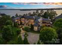 Elegant lakefront property at dusk showcases exterior lighting, mature trees and landscaped front yard at 18019 Harbor Light Blvd, Cornelius, NC 28031