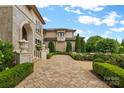 Stone pathway leads to a grand home entrance with decorative urns, manicured hedges, and lush landscaping at 18019 Harbor Light Blvd, Cornelius, NC 28031