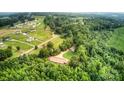 Aerial view showcasing the property's boundaries, home, outbuilding, and surrounding mature trees at 6051 Pointe West Ln, Vale, NC 28168
