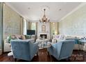 Bright living room with a fireplace, chandelier, and serene wallpaper for a comfortable and stylish space at 4016 Nettie Ct, Charlotte, NC 28211