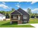 Inviting home with a covered porch, dark siding, white trim, and a spacious green lawn at 213 Sheffield Dr, York, SC 29745