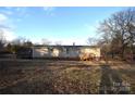 Back view of the mobile home with a large yard and wooden deck at 4223 Old Catawba Rd, Claremont, NC 28610