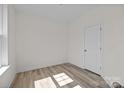 Simple bedroom with light hardwood floors, natural light, and a white door at 4210 Alexander View Dr # 38, Charlotte, NC 28226