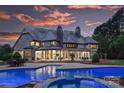 Back exterior of home at dusk showcasing the pool and spa with lights on, and the multiple patios at 525 Lake Lynn Rd, Concord, NC 28025