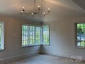 Bright living room featuring multiple windows, a vaulted ceiling with a modern chandelier, and pristine hardwood floors at 1969 Maryland Ave, Charlotte, NC 28209
