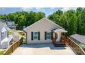Inviting single-story home with a charming front porch and a concrete driveway nestled among lush trees at 159 Badin Lake Cir, New London, NC 28127